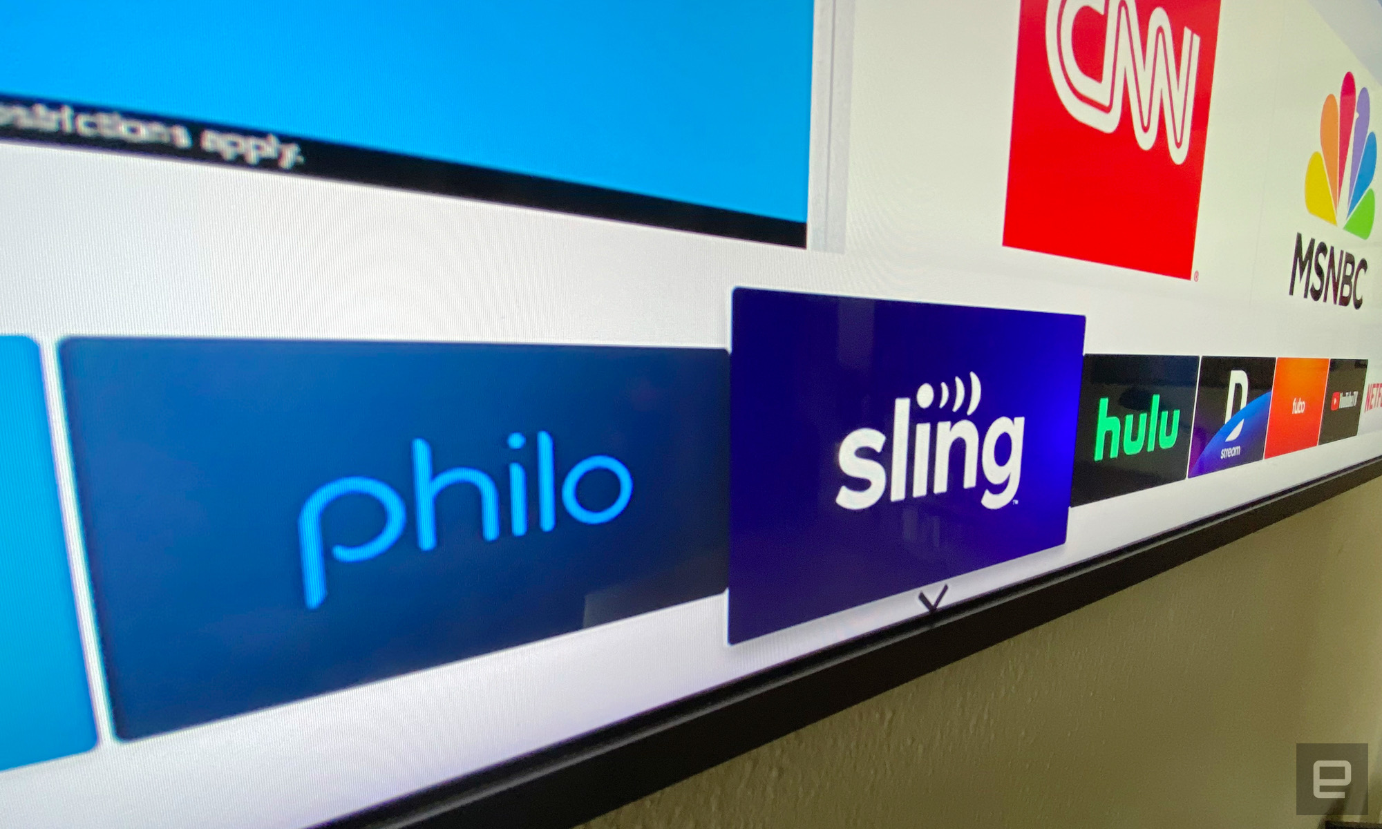 A TV displaying the logos for Philo, Sling, Hulu, DirecTV stream, fuboTV, and YouTube TV apps.